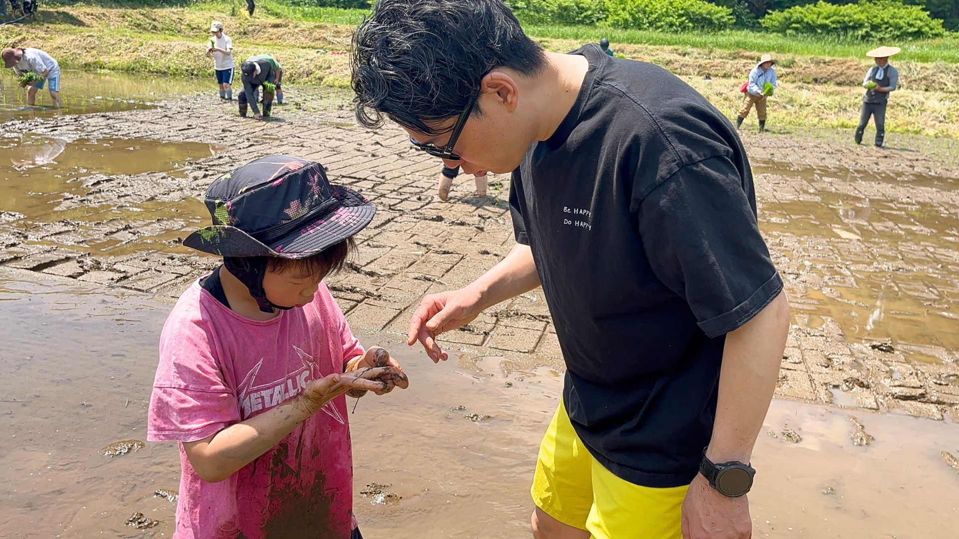 田んぼの周りで生きもの探しをする子ども