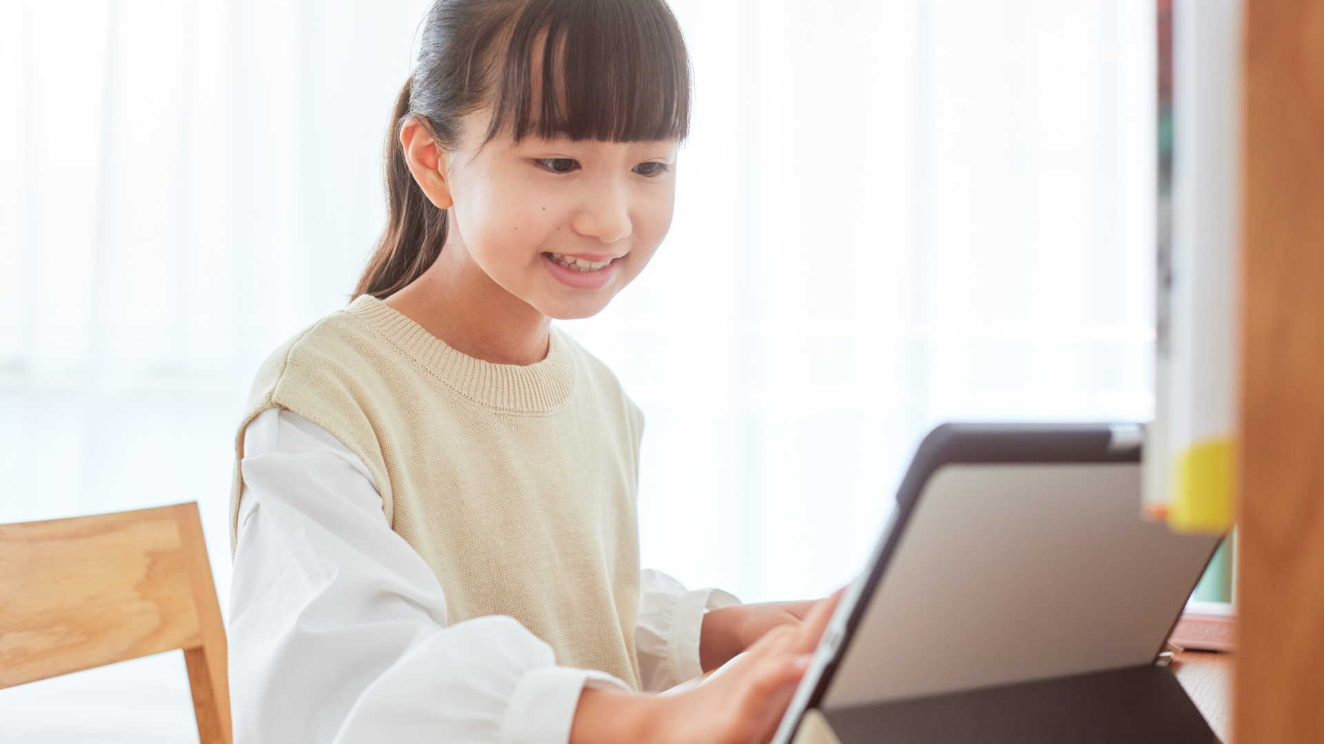 学童に行きたくない子どもが自宅でタブレットを使って過ごす様子の写真